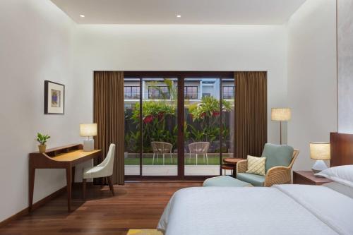 a hotel room with a bed and a desk and chair at Sheraton Grand Chennai Resort & Spa in Mahabalipuram