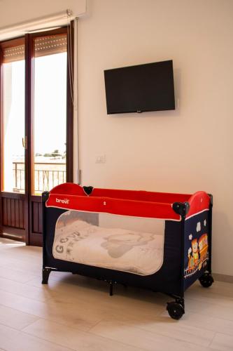 a small bed in a room with a tv on the wall at Casa Baí in Torre Nubia