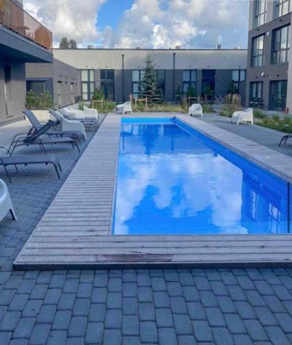 a swimming pool with a deck and chairs and a building at Black IN Palangos loftai in Palanga