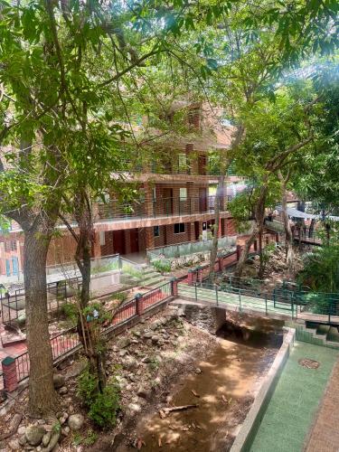 a park with benches and a river in front of a building at Hotel El Bosque Valledupar in Valledupar