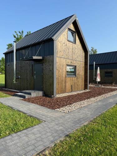 a timber clad house with a black roof at Łąkowe Wzgórze in Kosewko