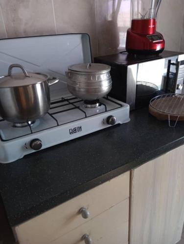 a stove with two pots and pans on a counter at Eliogemi Gardens Guests House in Gbawe