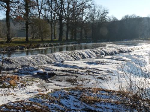 une rivière gelée avec de la neige sur le côté dans l'établissement Maison de vacances, à La Celle-sous-Gouzon