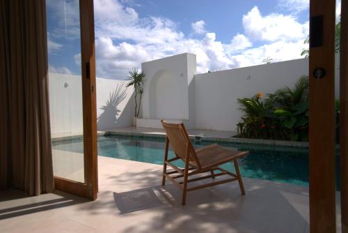 una silla sentada en un porche junto a una piscina en Stylish New Villa close to the beach, en Uluwatu