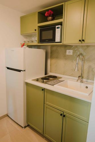 a kitchen with a white refrigerator and a sink at Écrin bleu - Vue mer & piscine in La Marsa