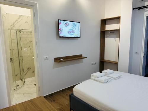 a bathroom with a shower and a bed with towels at Hotel LBC in Sarandë