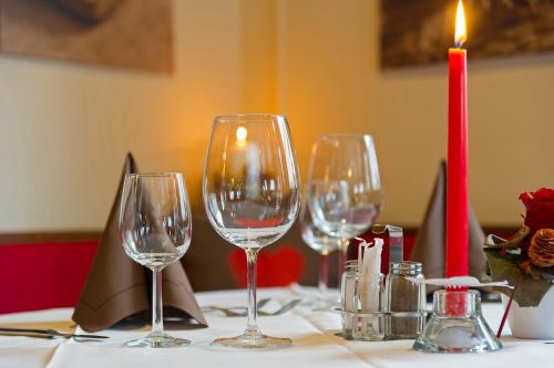 four wine glasses sitting on a table with a candle at Hotel Mondschein in Sesto