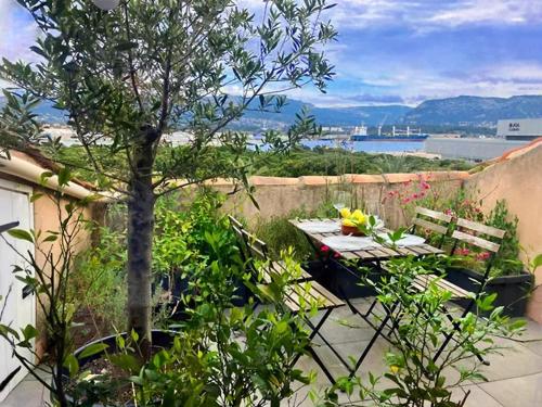 d'une terrasse avec une table, des bancs et un arbre. dans l'établissement Appartement contemporain à La Seyne-sur-Mer, 30 m², terrasse, à La Seyne-sur-Mer