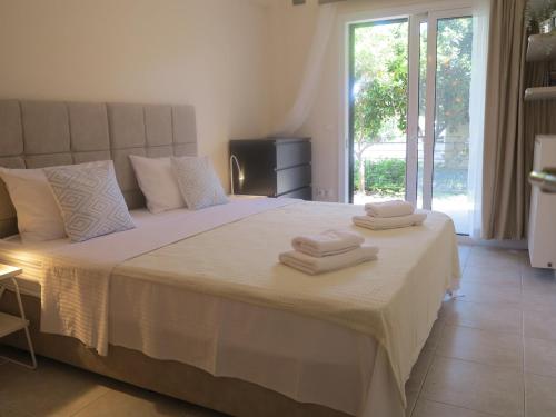 ein Schlafzimmer mit einem weißen Bett mit Handtüchern darauf in der Unterkunft ELIRA - City Apartment, Lefkada in Lefkada Town