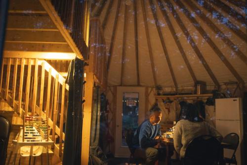 a man and woman sitting at a table in a yurt at Cozy Yurt in the Woods in Sainte-Agathe-des-Monts