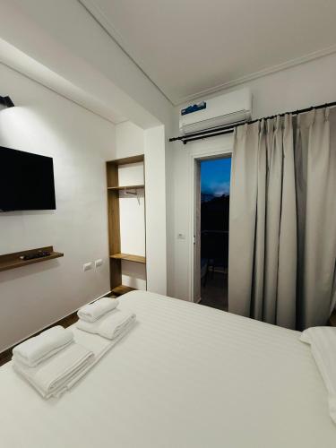 a bedroom with a white bed and a television at Hotel LBC in Sarandë