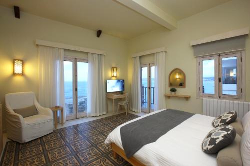 a bedroom with a bed and a chair and windows at Dar Alma in Soûr