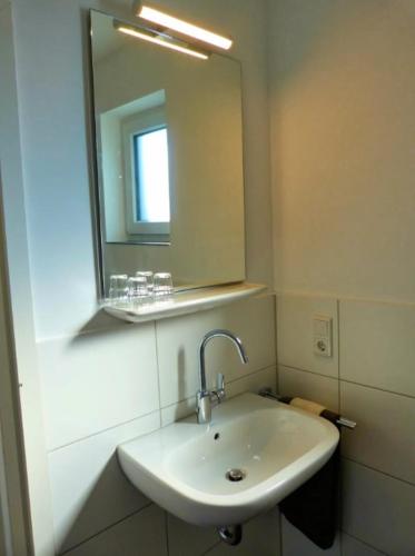 a bathroom with a sink and a mirror at Hempen Fied Gästehaus - Apartment 4 in Bad Zwischenahn