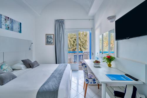 a white bedroom with a bed and a table at Hari Club Beach Resort in Aghīr