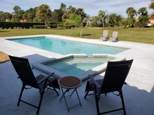 a swimming pool with two chairs and a table and two chairs at Chasing Buoys at Swiss in Clermont