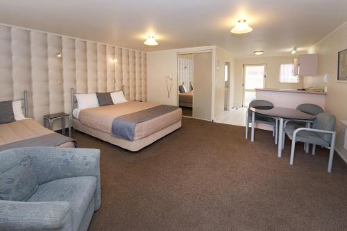 Una habitación de hotel con una cama, una mesa y un sofá. en Geneva Motor Lodge, en Rotorua
