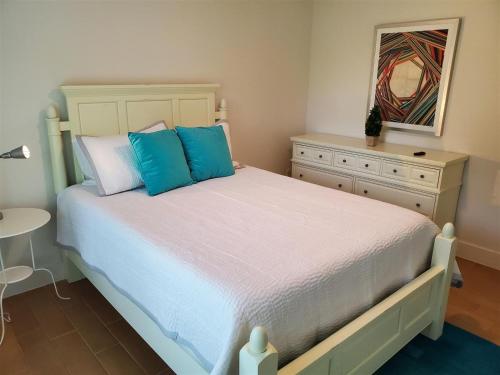 a bedroom with a bed with blue pillows and a dresser at Chasing Buoys at Swiss in Clermont