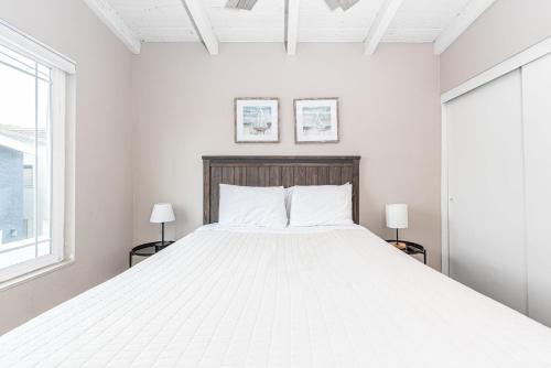 a white bedroom with a large bed with two lamps at Pet-Friendly 3Br W Oceanview Balcony & Bbq Steps To Beach By Beachview Rentals in Newport Beach