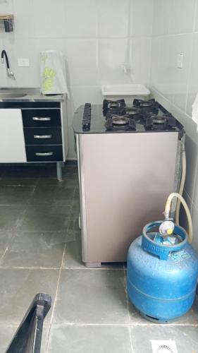 a kitchen with a stove and a blue bucket at Sua Praia seu lar in Itanhaém
