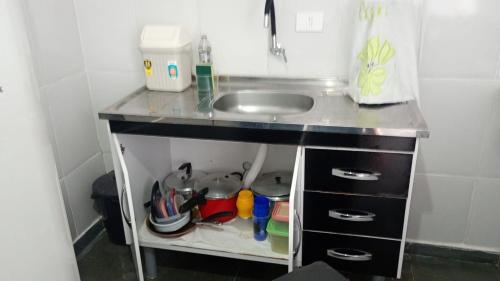 a small kitchen with a sink and a counter top at Sua Praia seu lar in Itanhaém