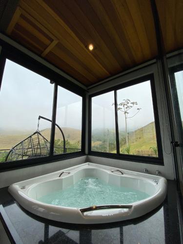 a bath tub in a room with three windows at Villa Mantiqueira SFX - Cabanas in São José dos Campos