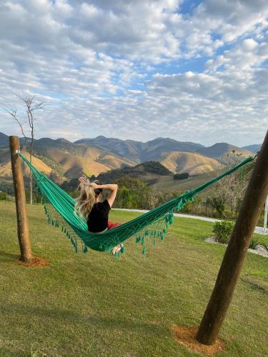 a woman laying in a hammock in a field at Villa Mantiqueira SFX - Cabanas in São José dos Campos