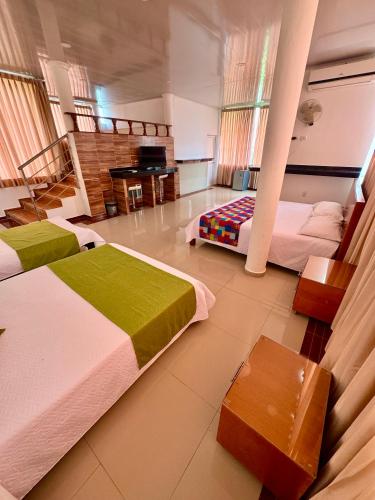 a hotel room with two beds and a piano at Hotel El Bosque Valledupar in Valledupar