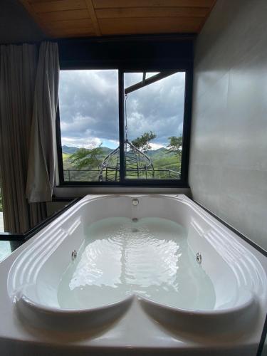 a bath tub in a room with a window at Villa Mantiqueira SFX - Cabanas in São José dos Campos
