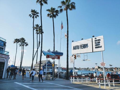 a group of people walking around a marina with palm trees at Charming 2Br Condo W Ac Steps To Beach & Balboa Pier By Beachview Rentals in Newport Beach