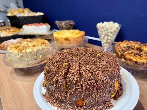 a chocolate cake on a plate on a table with other cakes at ibis budget Divinopolis in Divinópolis
