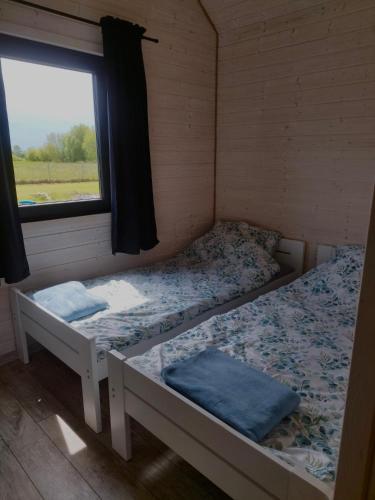 two beds in a room with a window at Domki Pod Świerkami in Jezierzany