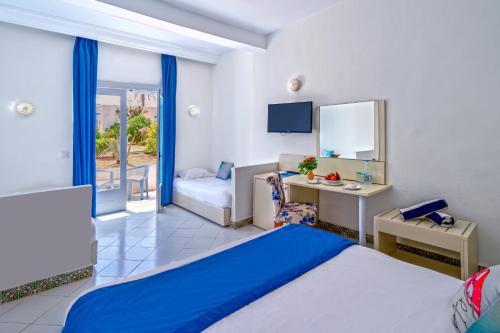 a bedroom with a bed and a desk and a chair at Hari Club Beach Resort in Aghīr
