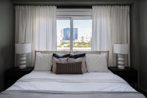 a bedroom with a bed with pillows and a window at 9+Ocho Suites by Yellowkey in Santo Domingo