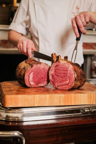 a person cutting a piece of meat on a cutting board at The Shelbourne, Autograph Collection in Dublin