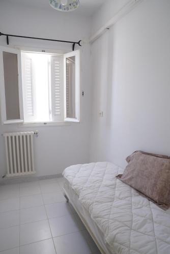 a white bedroom with a bed and a window at Belle maison avec jardin à Hammamet in Hammamet Sud