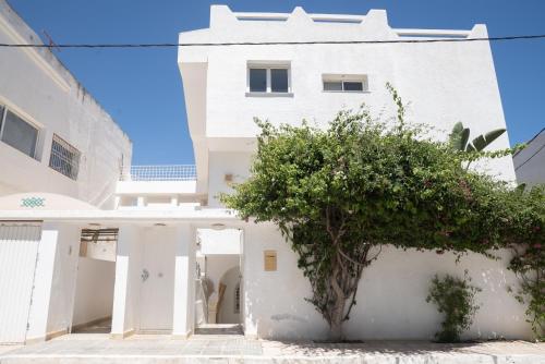 a white house with a tree in front of it at Belle maison avec jardin à Hammamet in Hammamet Sud
