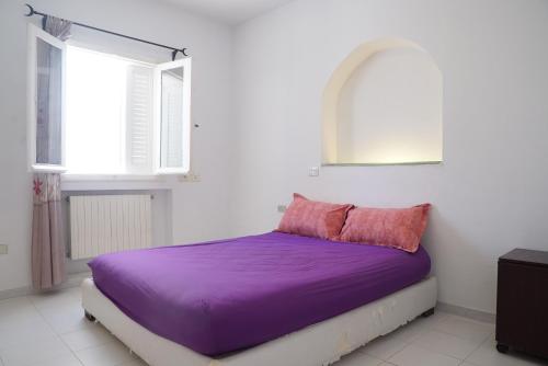 a bed with purple sheets in a room with windows at Belle maison avec jardin à Hammamet in Hammamet Sud