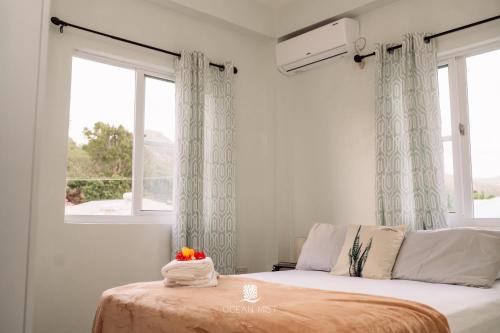 a bedroom with a bed and a window with curtains at Ocean Mist Suites in Arnos Vale