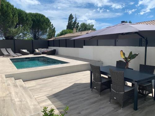 une terrasse avec une table, un parasol et une piscine dans l'établissement Maison agréable pour vacances réussies, à Vernègues