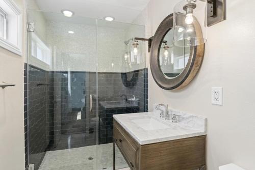 a bathroom with a shower and a sink and a mirror at Modern 3Br Oceanfront W Rooftop Deck & Panoramic Views By Beachview Rentals in Newport Beach