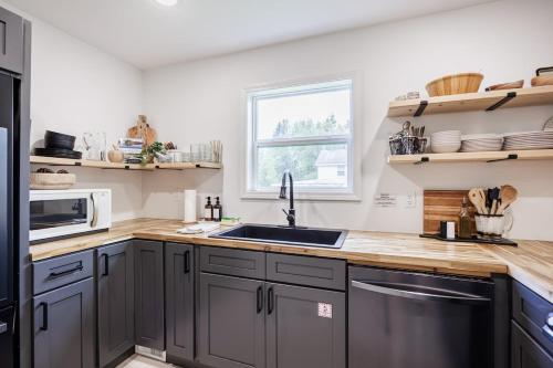 a kitchen with gray cabinets and a sink at Watkins Glen Luxury Escape on Seneca Wine Trail in Watkins Glen