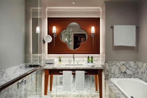 a bathroom with a sink and a tub and a mirror at St Pancras London, Autograph Collection in London