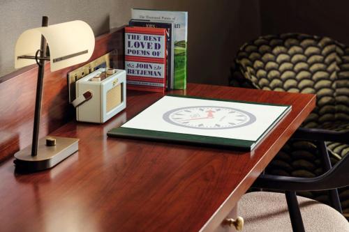 a desk with a lamp and a book on it at St Pancras London, Autograph Collection in London