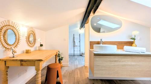 La salle de bains est pourvue d'un lavabo et d'une coiffeuse avec un miroir. dans l'établissement 151 - Terrasse & Jacuzzi, Rue Trivalle, Pied de la cité de Carcassonne - Climatisation, Netflix, Fibre, à Carcassonne