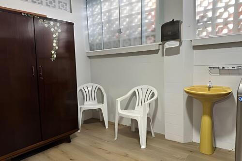 a bathroom with two chairs and a yellow sink at Excelente casa familiar no Centro FW in Pomerode