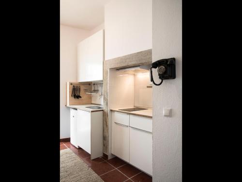 a small kitchen with white cabinets and a refrigerator at Nooks Apartment in Sintra