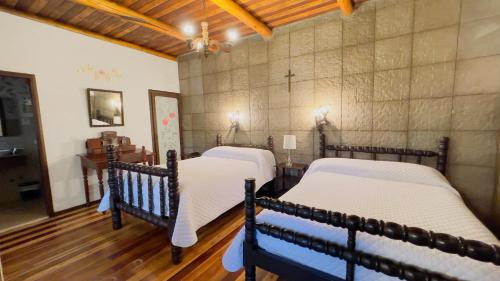 two beds in a room with wooden floors at Hacienda Hosteria Chorlavi in Ibarra