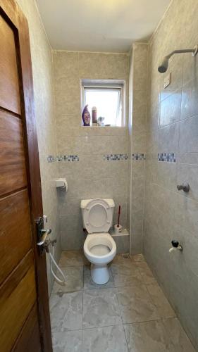 a bathroom with a toilet and a shower and a window at DRE'S WORLD STAYs in Mombasa