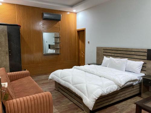 Jharoka Resort - Taranna, Balakot في Hassa: غرفة نوم بها سرير أبيض كبير وكرسي