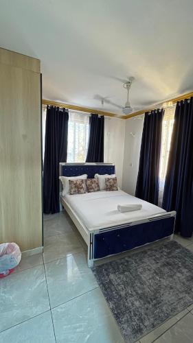 a large bed in a room with blue curtains at DRE'S WORLD STAYs in Mombasa